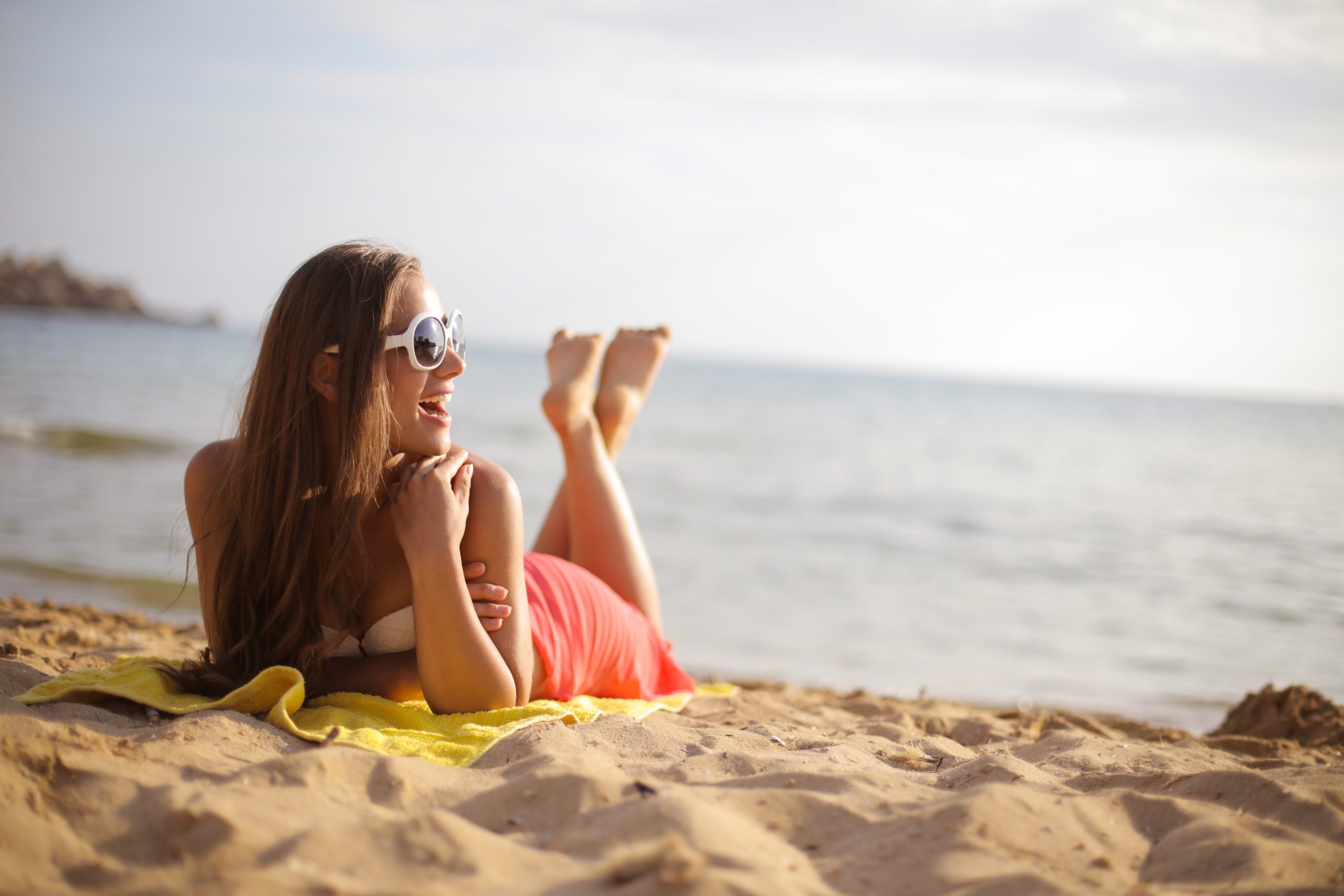 Mulher de biquíni branco aproveitando o dia de sol na praia
