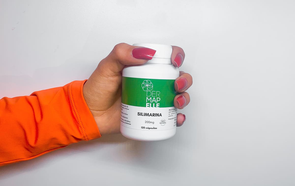Mão segurando um pote de Silimarina 200mg Dermapelle